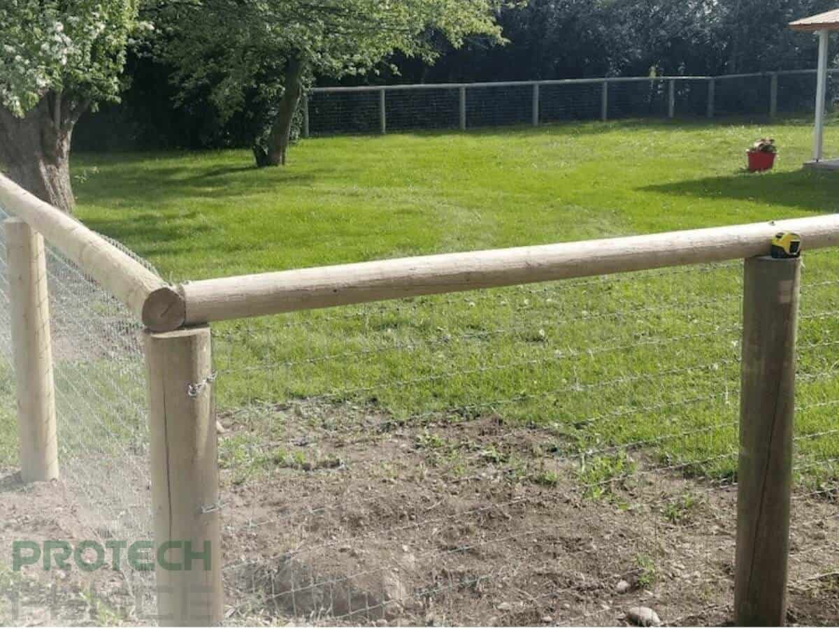A wood fence in Idaho Falls enclosing a yard, featuring sturdy thick wooden posts and chicken wire panels. The rustic and durable design of this wood fence installation provides a secure boundary for the property.