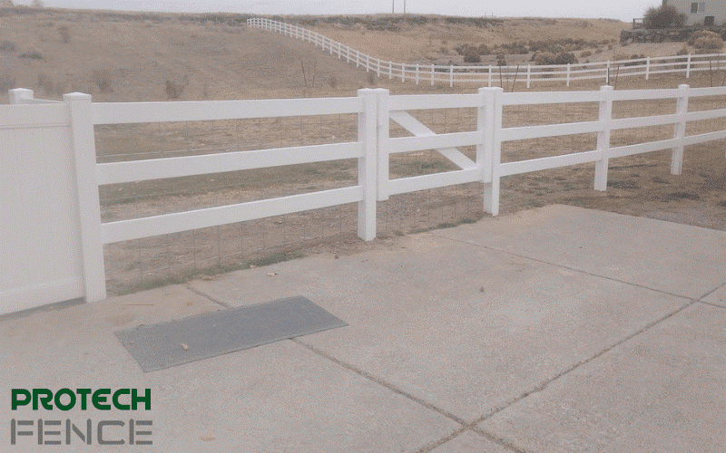 A scenic view of a ranch rail vinyl fence installation by Protech Fence Company stretching across a large property, featuring wire threaded through the openings for added functionality and security.