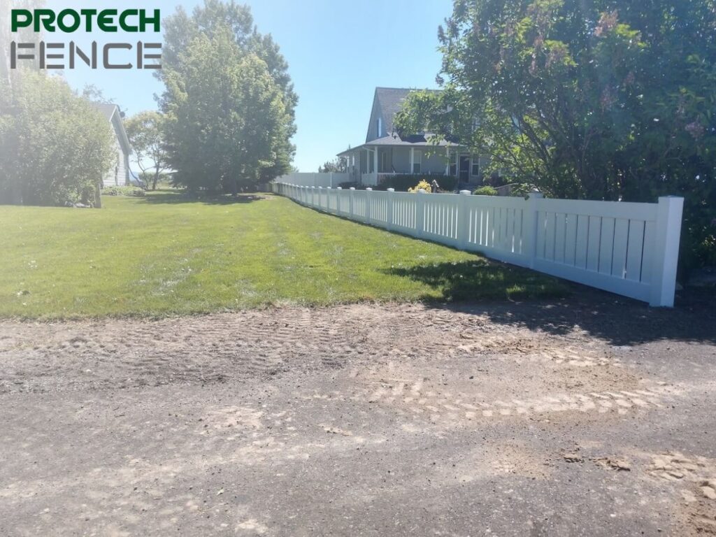 A 4 foot vinyl privacy fence installed along a lush green lawn with Protech Fence logo at the top left corner, showcasing the smooth white panels and clean lines providing privacy and enhancing the property's curb appeal.