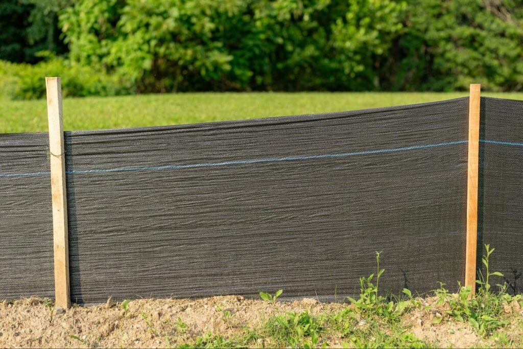 A professionally installed silt fence by silt fence installation companies, including Protech Fence Company, designed to control erosion and sediment runoff in a grassy area.
