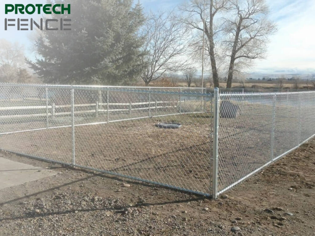 A sturdy chain link fence installed by chain link fence company Pocatello, Protech Fence, encloses a large grassy area, illustrating the company's skill in providing secure and visible fencing solutions for public and industrial spaces.