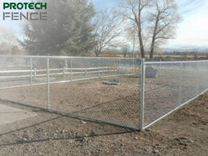 A sturdy chain link fence installed by chain link fence company Pocatello, Protech Fence, encloses a large grassy area, illustrating the company's skill in providing secure and visible fencing solutions for public and industrial spaces.