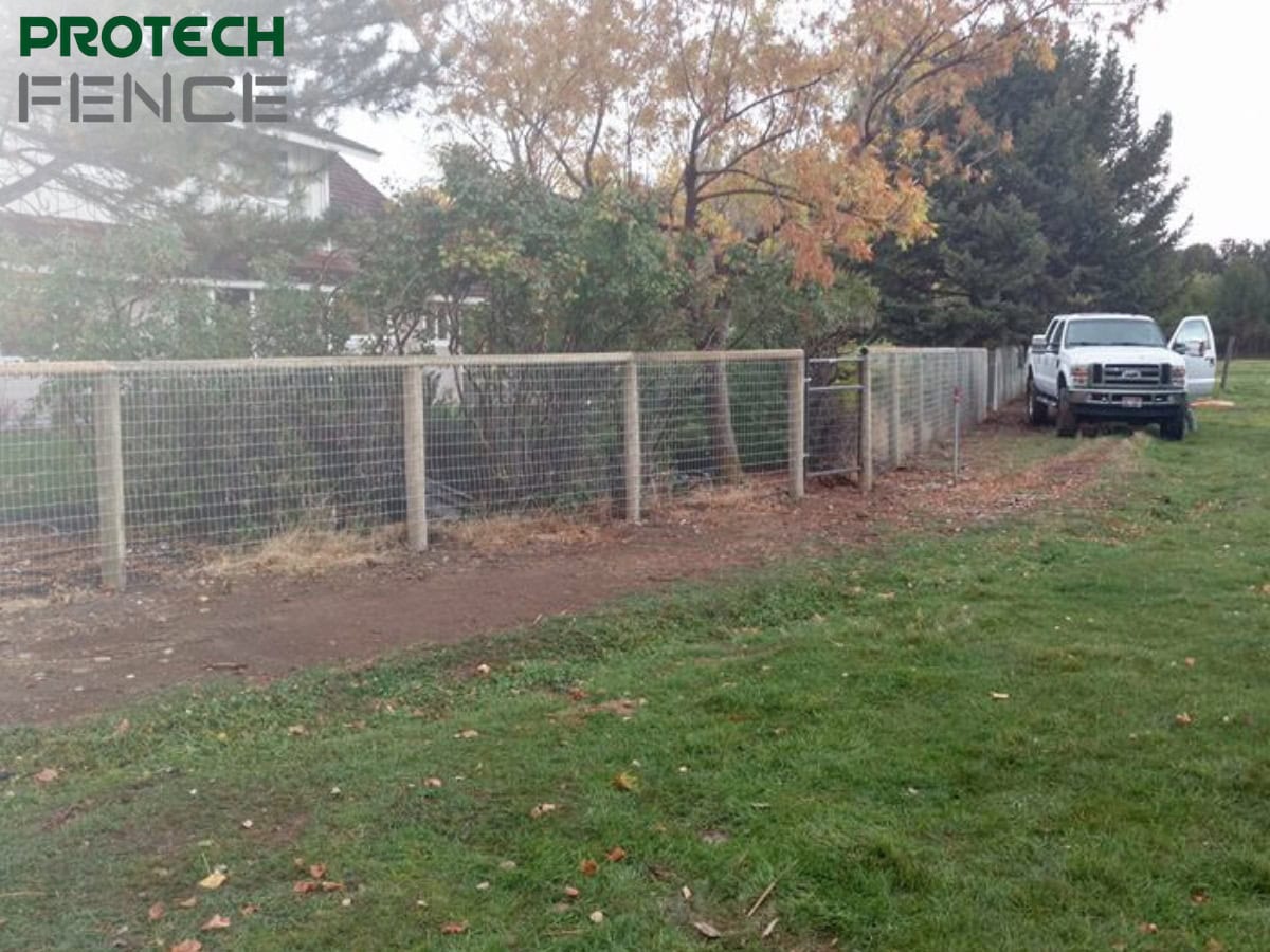 A newly installed metal wire fence in a suburban backyard, with a white pickup truck indicating work by one of the fencing companies that offer financing in Pocatello. 