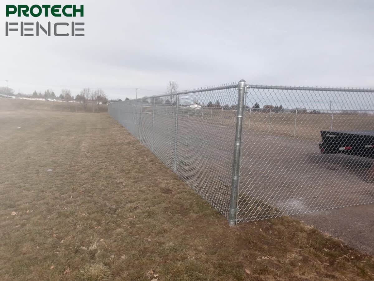 A residential chain link fence by chain link fence companies Pocatello encircles a green backyard, showcasing a secure and open area that maintains natural aesthetics while providing safety. 