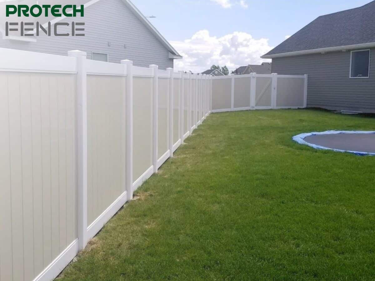 Elegant white vinyl fencing installed by a top fence company in Pocatello, enhancing the backyard privacy of a suburban home, with the Protech Fence logo displayed in the upper left corner. 