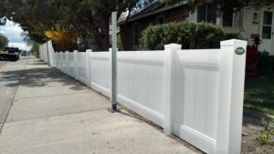 Fence Financing by Protech Fence Company. In image of a white vinyl privacy fence by Protech installed separating a property and the public sidewalk.